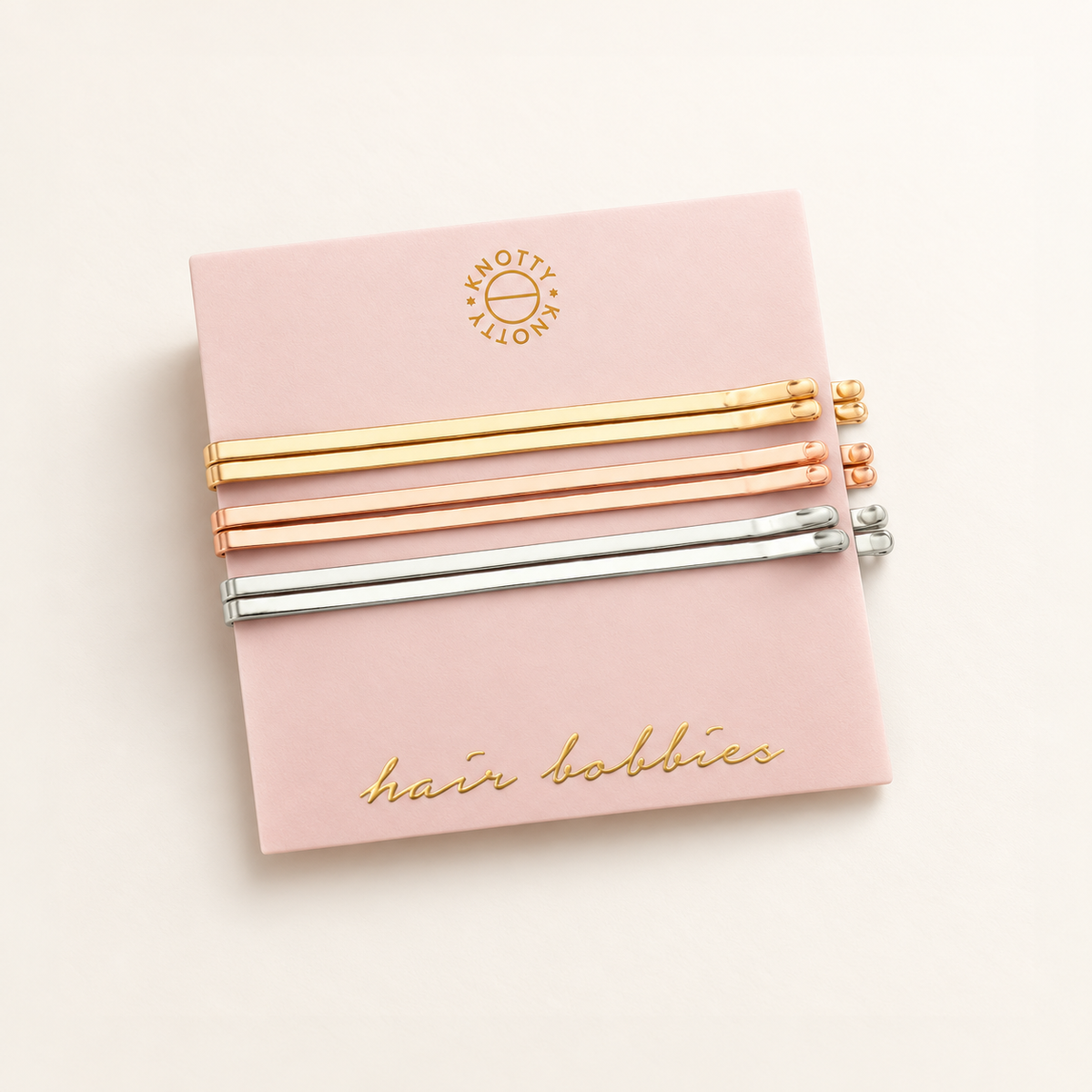 Six metallic hair bobbies in gold, rose gold and rhodium finishes on their pink card